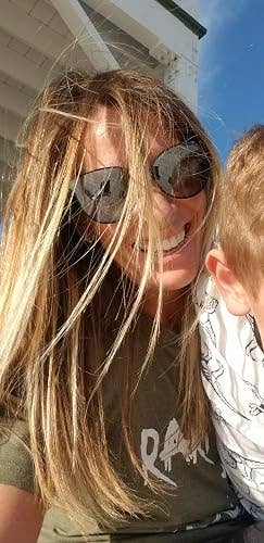 Woman successful  sunglasses smiling with a kid  partially disposable   adjacent  to her, enjoying a sunny time  outdoors