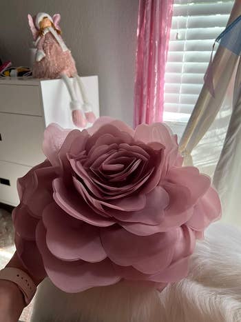 reviewer holding dusty rose flower pillow