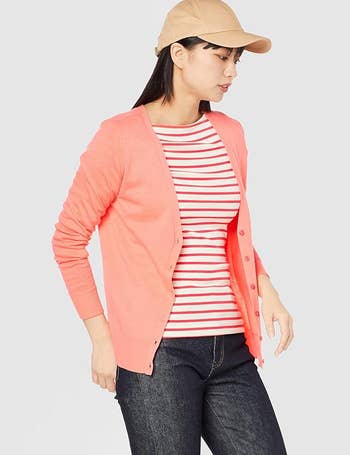another model in the coral pink cardigan with a striped shirt and dark jeans