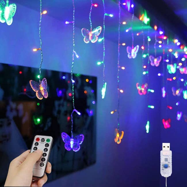 Butterfly shaped lights hanging from a ceiling being operated by a small remote 