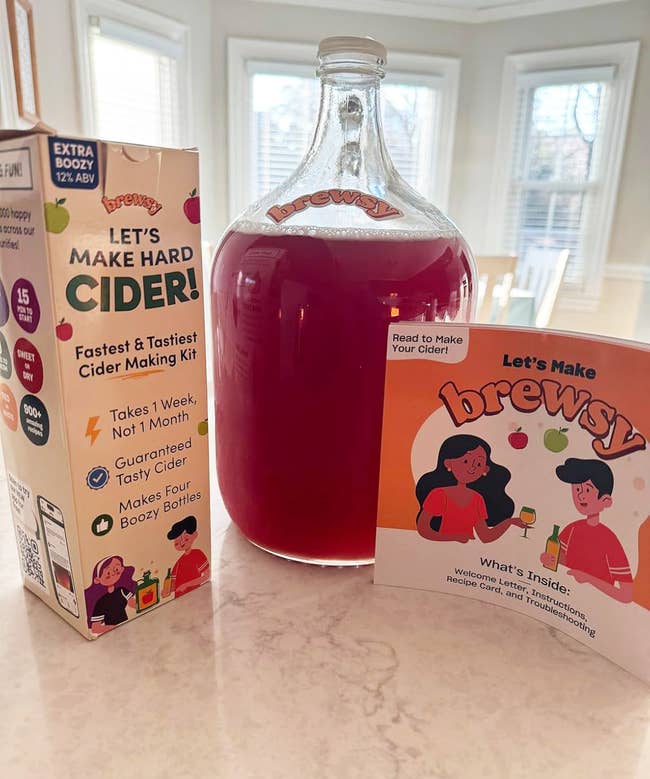 Brewsy hard cider making kit displayed with vessel and acquisition booklet, promising cider successful 1 week. Comes with look cards and troubleshooting tips