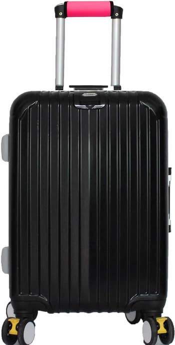 A black suitcase with pink luggage handle