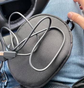 Reviewer with the case and cable to charge it on their lap