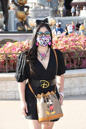 a reviewer wearing a black dress with the thick black disney belt with a 'D' buckle