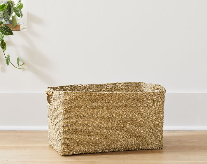 Gold metallic basket on hardwood floor in front of window with plant on ledge