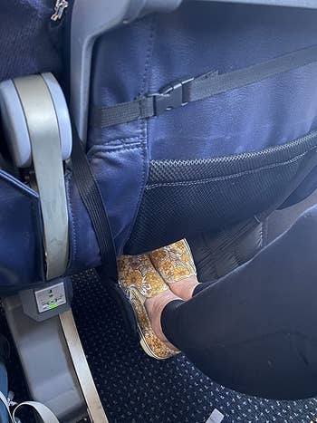reviewer using the foot hammock on a flight