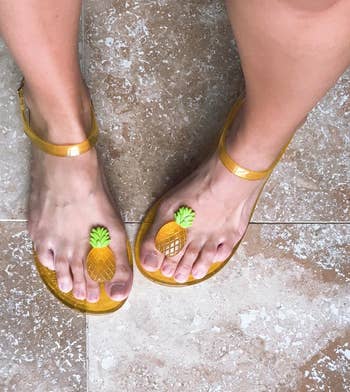 reviewer wearing the ankle-strap flats in yellow with pineapples between the big and second toe