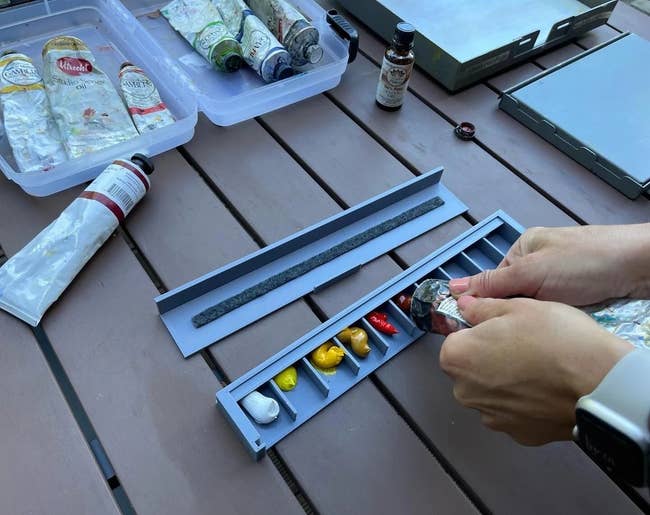 hand squirting paint from a tube into a section of the organizer