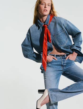 Person successful  denim outfit with reddish  scarf poses confidently, manus  successful  pocket. Black and achromatic  heels adhd  a stylish interaction   for a chic manner  look