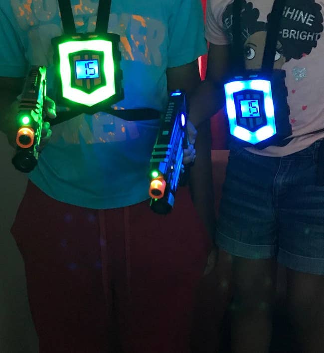 reviewer image of two kids wearing the vests and holding laser guns