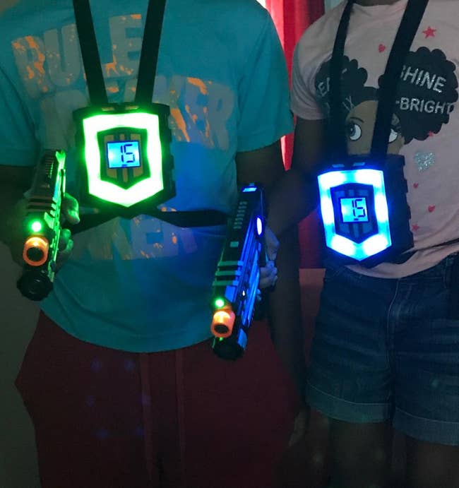 reviewer image of two kids wearing the vests and holding laser guns