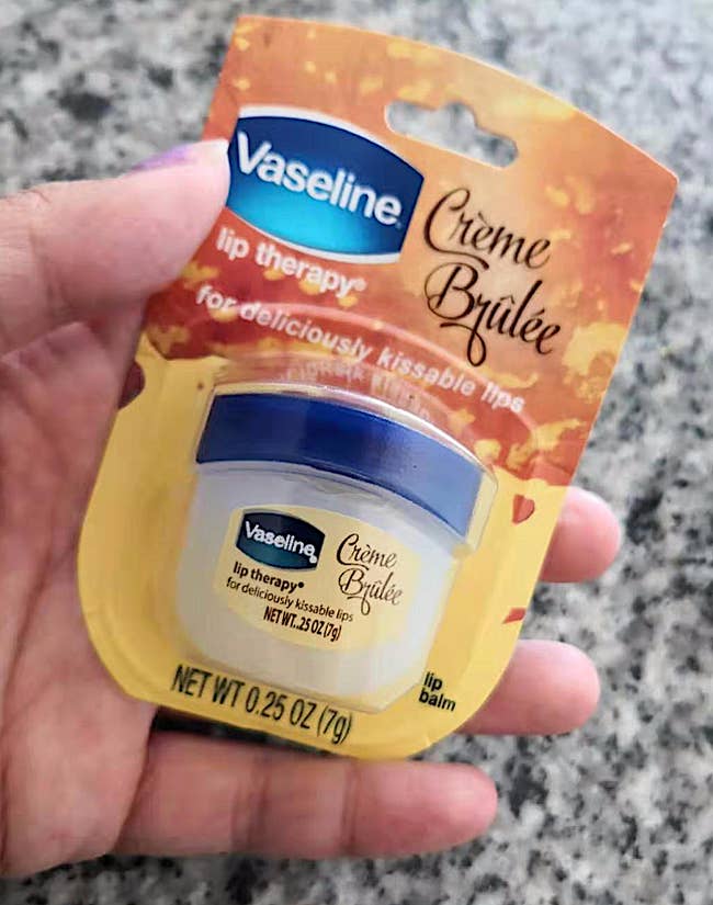 Hand holding Vaseline Crème Brûlée Lip Therapy package, labeled for