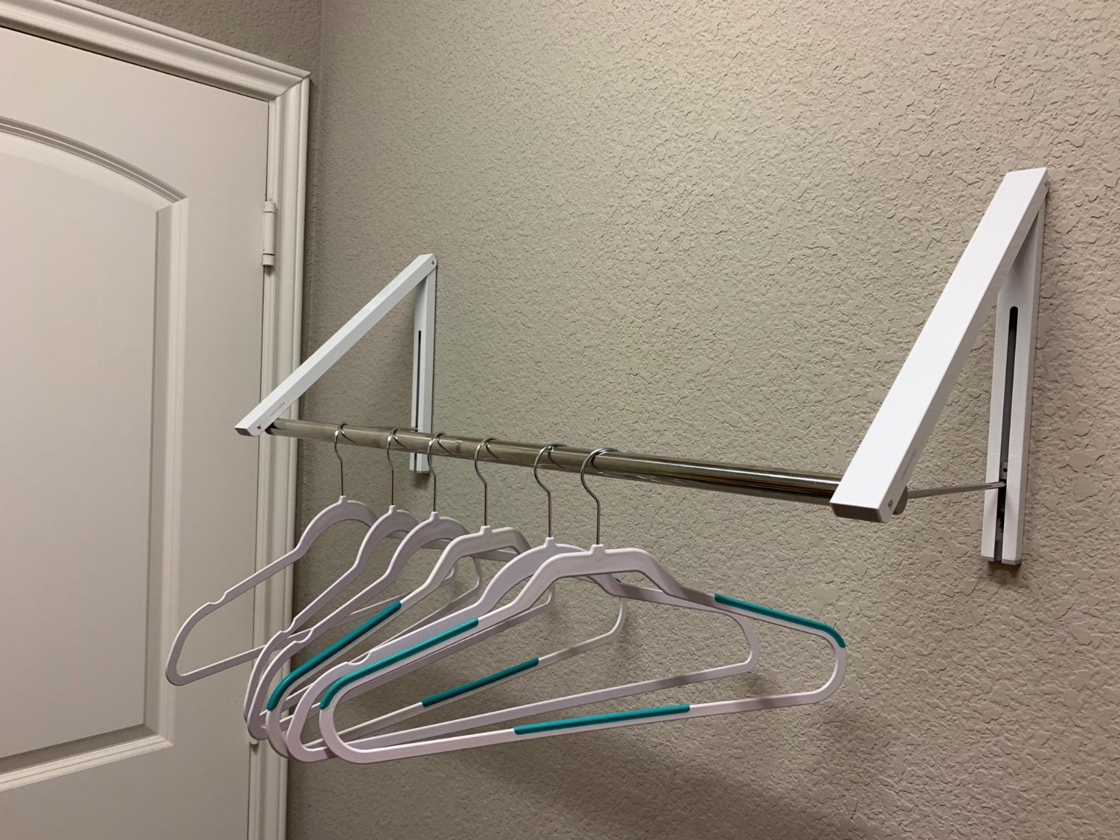 same reviewer's photo of the clothes rack with the clothing bar holding several empty hangers