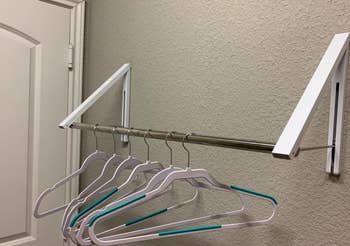 same reviewer's photo of the clothes rack with the clothing bar holding several empty hangers
