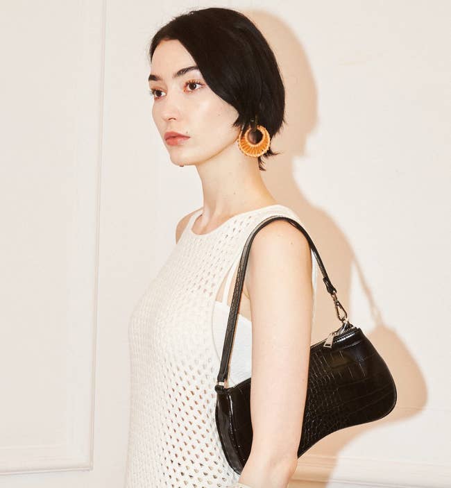 model wears black faux croc material shoulder bag