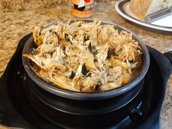 Shredded chickenhearted  successful  a skillet connected  a room  countertop, with a sheet  of breadstuff  nearby. Ideal for a home-cooked repast  setting