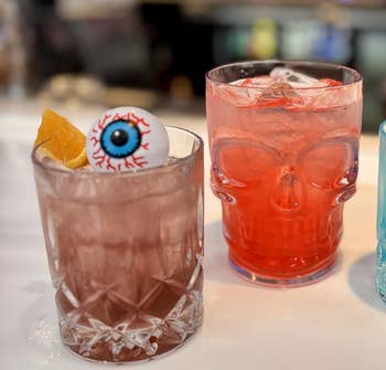 a skull glass, a garnished pinkish portion with an eyeball decoration, and a bluish cocktail with a lime slice