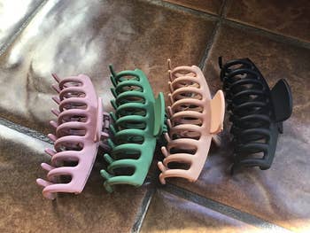 reviewer photo of the four colorful claw clips lined up on the floor
