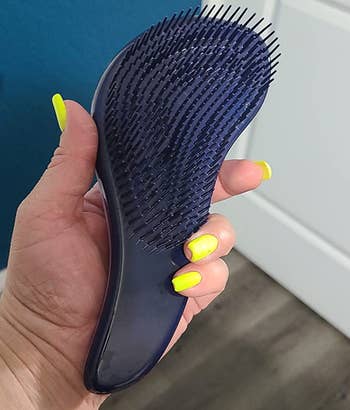 reviewer holding the s-shaped detangling brush