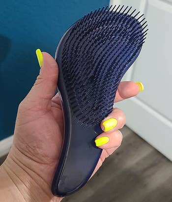 reviewer holding the s-shaped detangling brush