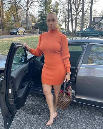 Reviewer is wearing the ribbed bodycon sweater dress in an orange color