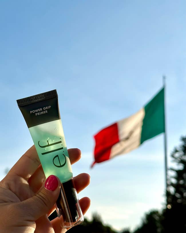 Hand holding e.l.f. Power Grip Primer with a emblem successful the inheritance against a wide sky.