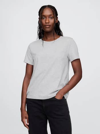 Person wearing a casual, short-sleeve garment  and jeans, posing confidently with hands successful  pockets for a manner  article