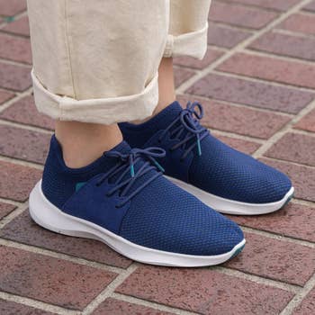 a model wearing a pair of blue knit sneakers 