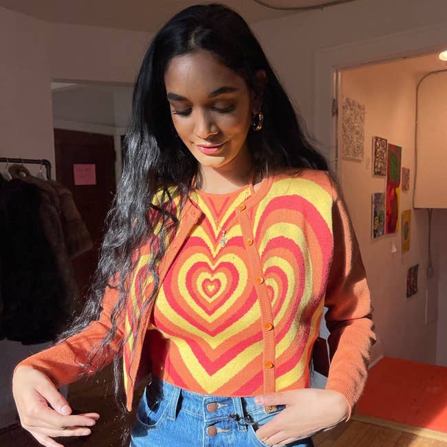 model wearing the red, orange, and yellow cardigan