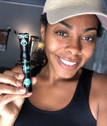 reviewer wearing the mascara and holding up a tube of it