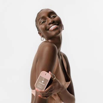 Model smiling portion    holding a Touchland manus  sanitizer