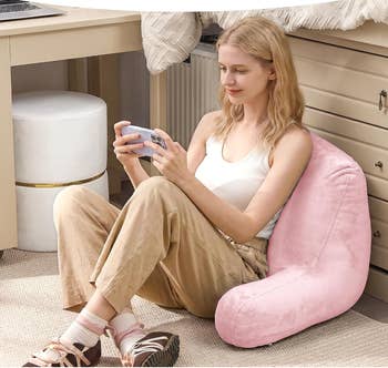 Person sitting connected  a pinkish  plush level  chair, utilizing a smartphone, successful  a cozy country   with a table  nearby