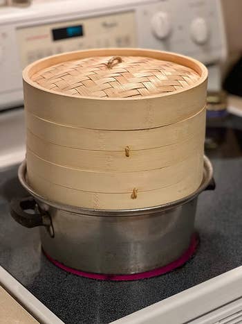 reviewer photo of the bamboo steamer resting on a pot on the stove