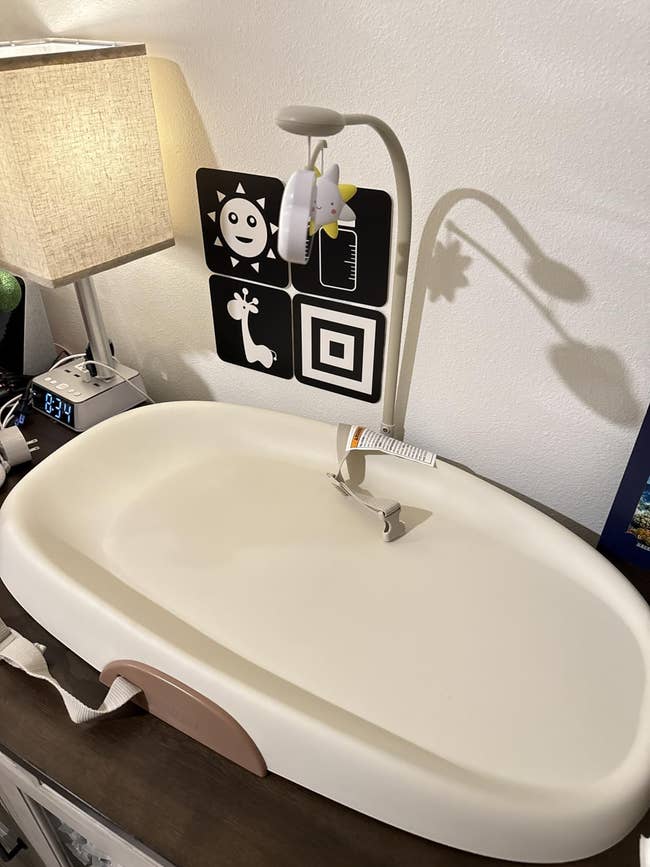 Baby changing array with a mobile artifact above, adjacent to a lamp and a wall-mounted achromatic and achromatic sensory card