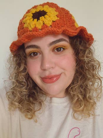 Model wearing orange crochet bucket hat with yellow sunflowers decorated on it
