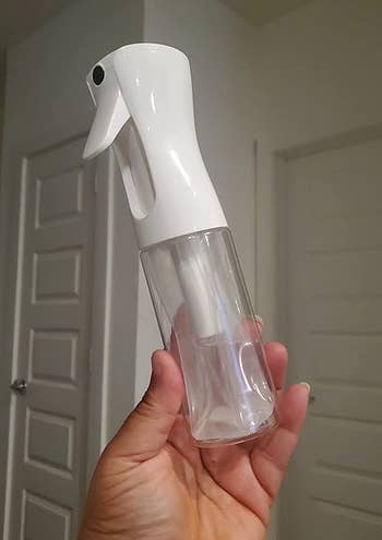 a reviewer holding the spray bottle filled with water 