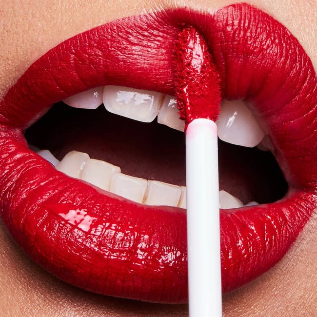 a model applying the bold red matte lipstick 