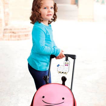 young girl pulling suitcase with alpaca luggage tag