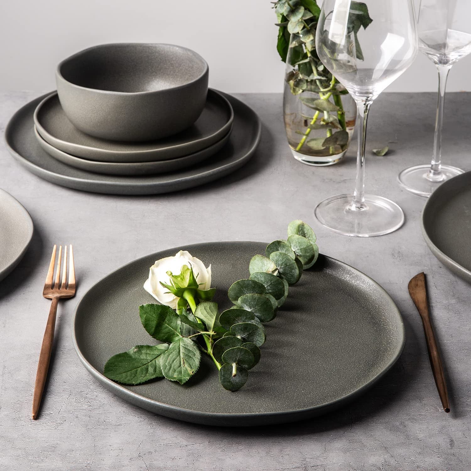 wavy ceramic dinner plate in grey with the entire set stacked behind it
