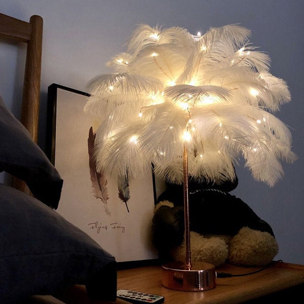 feathery lamp with fairy lights in it on bedside table