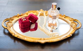 a reviewer's golden  reflector  tray with jewelry and perfume connected  it