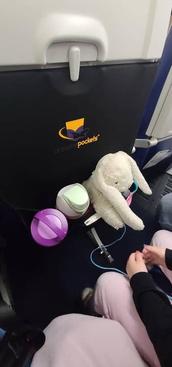 Travel accessories and a plush toy on an airplane seat tray for comfort and organization