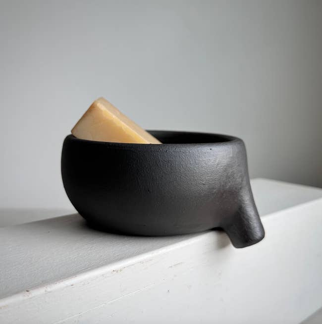 Black ceramic bowl shaped like an animal with a piece of soap inside, resting on a white surface for a modern look