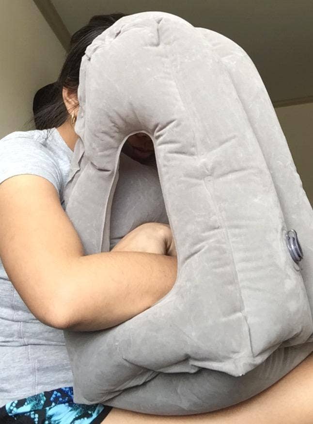 reviewer with their head resting on an inflated pillow that rests on their lap and has room for their arms