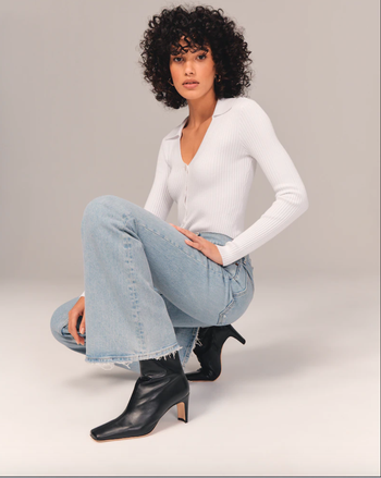 model squatting wearing black ankle boots and light wash flare jeans