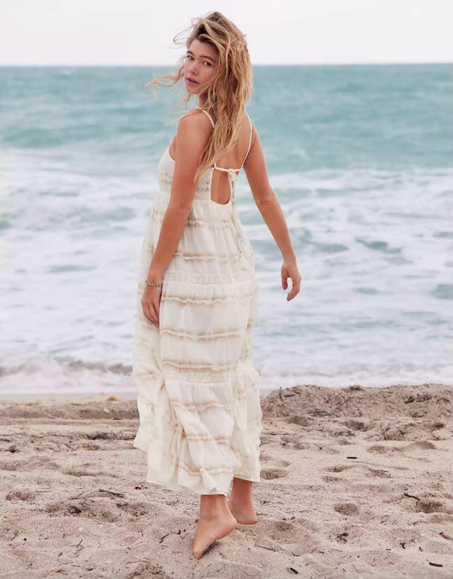 Model in an ivory and beige tie dye striped maxi dress with straps 