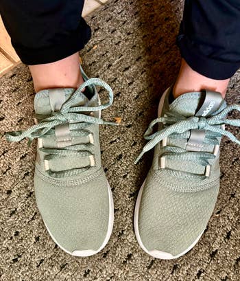 another reviewer wearing sneakers in silver green
