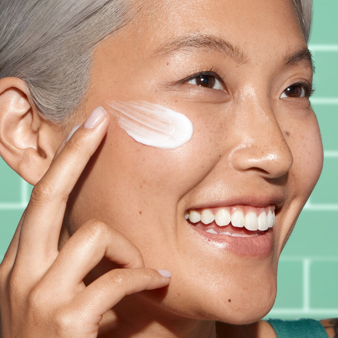 model with a swatch of white cream on their cheek