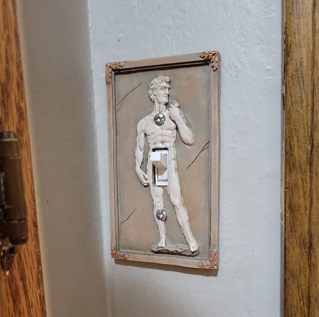 Sculpture of Michelangelo's David as a light switch cover, with the switch as part of the figure's torso