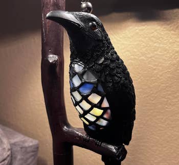 Decorative crow lamp with stained glass body on display, potentially available for purchase